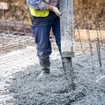 building construction worker pouring cement or concrete with pump tube